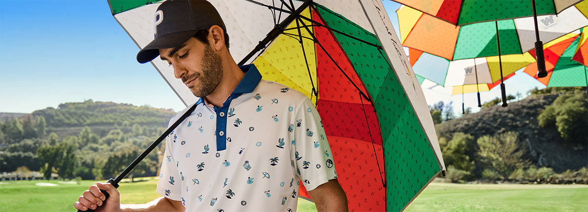 A man holds a multicolored umbrella on a golf course