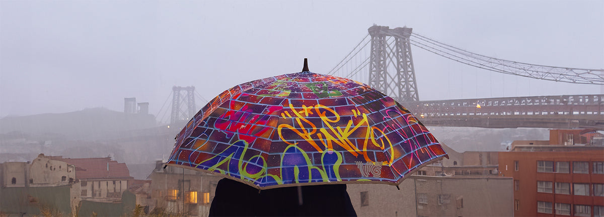 A man holding an umbrella with a combination of pink, blue, and yellow colors