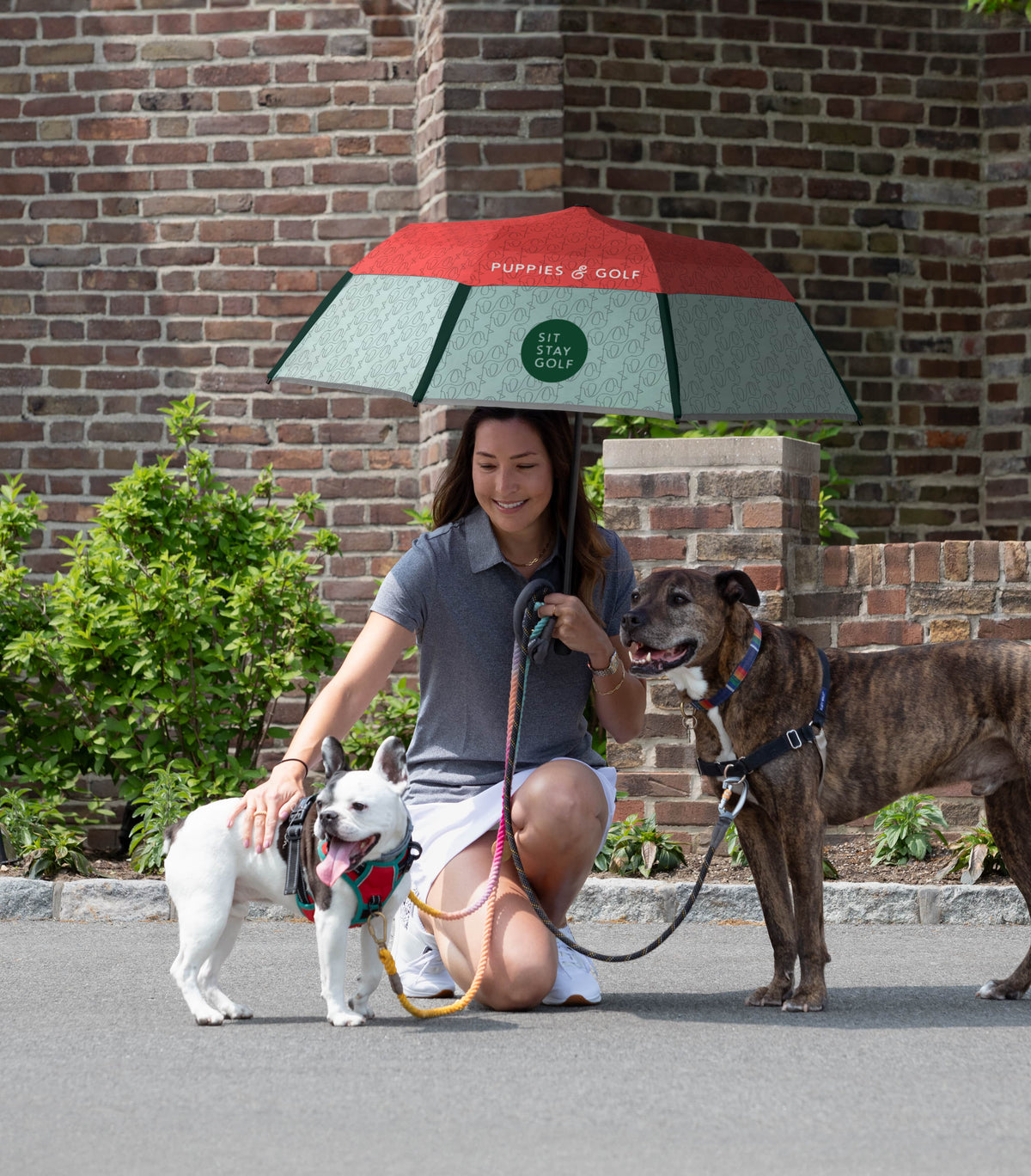 Woman sitting with dogs and holding a golf umbrella