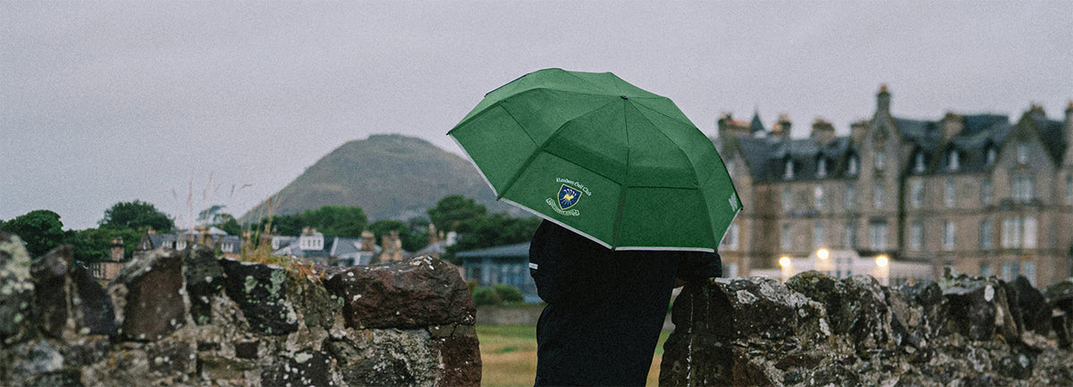 Man with a green umbrella near a mountain